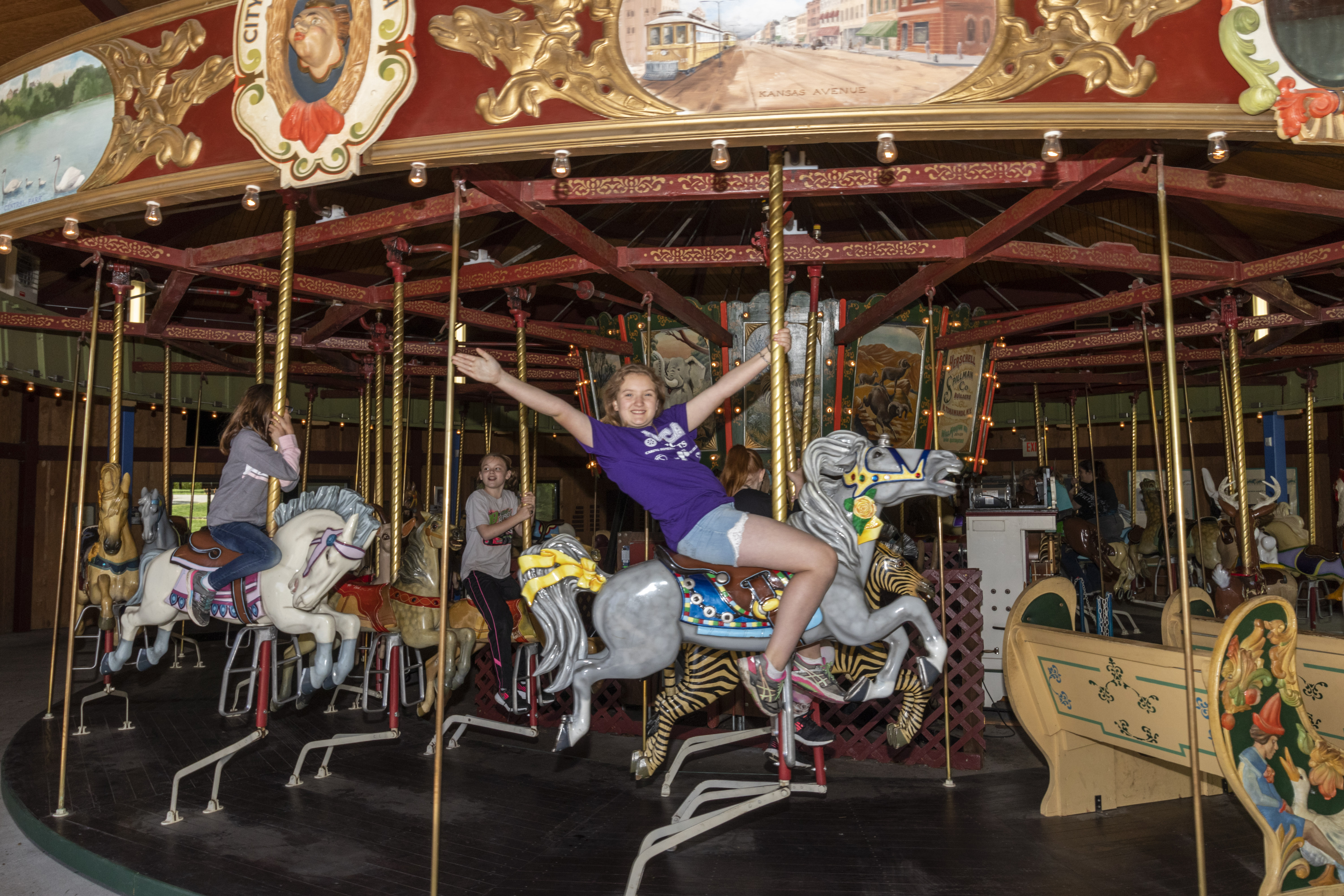 Little girl with outstretched hands riding carousel